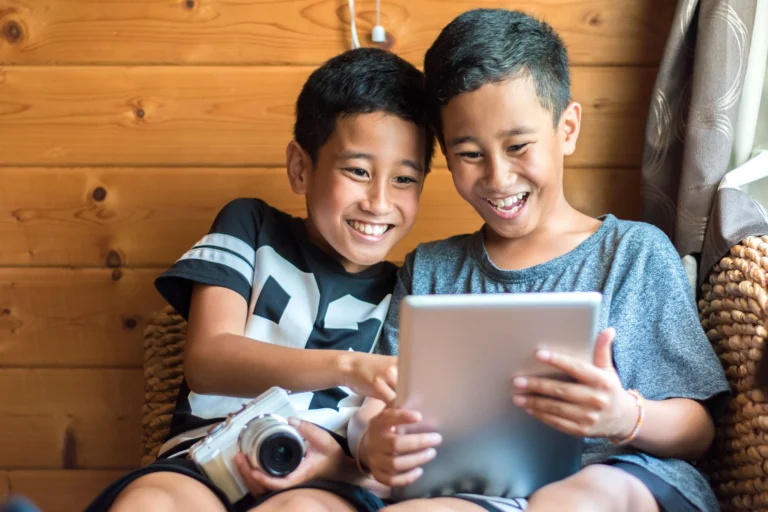 two boys happily playing with an iPad device