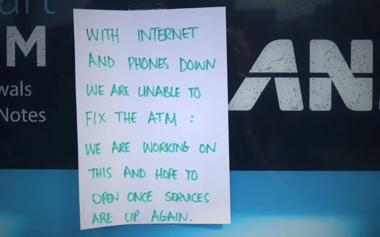 Handwritten sign taped to an ANZ ATM reading: "With internet and phones down we are unable to fix the ATM. We are working on this and hope to open once services are up again." The ANZ logo and partial ATM screen are visible behind the sign.